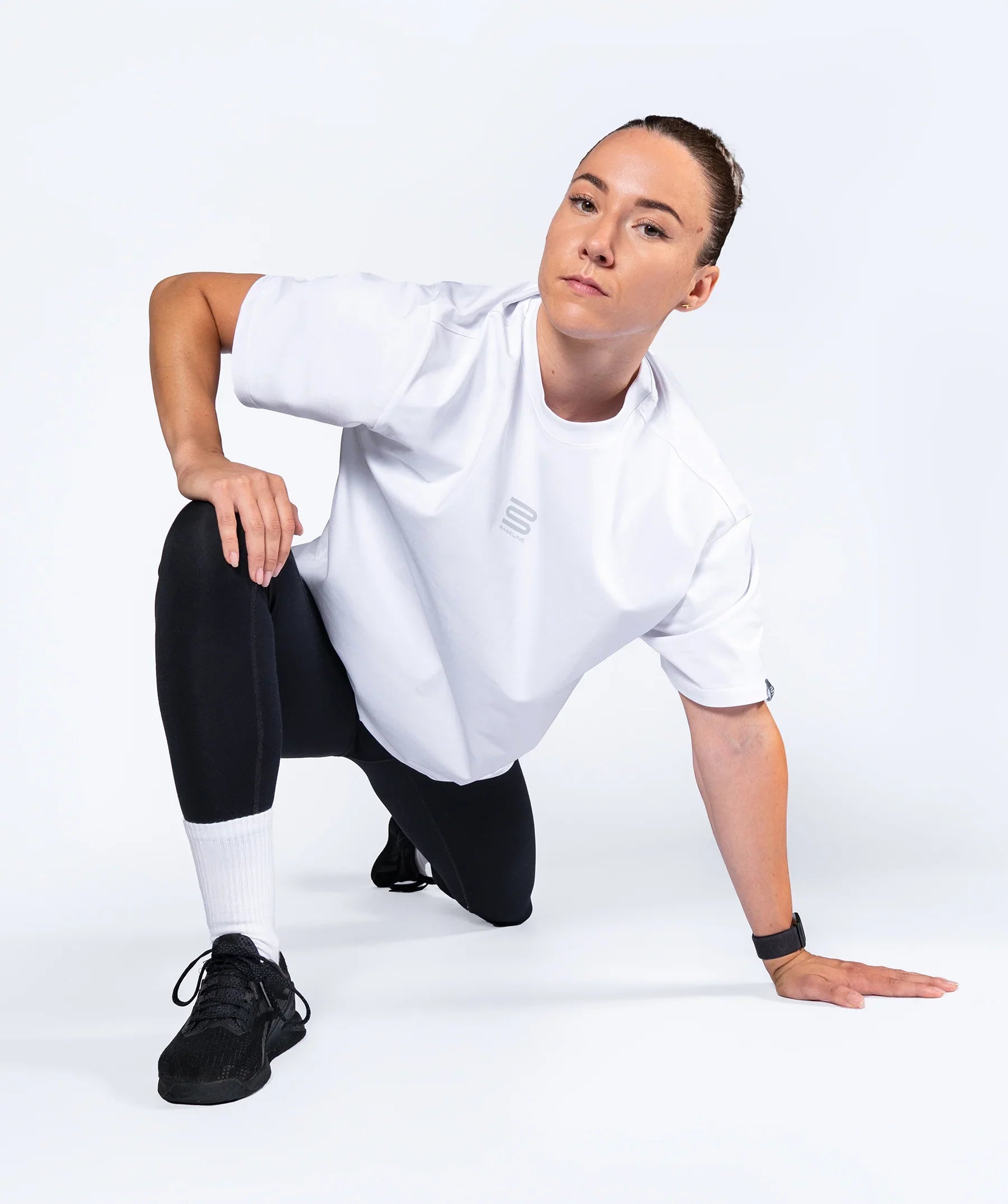 Female athlete in a white 'Centric Oversized' t-shirt and black pants posing on a white background