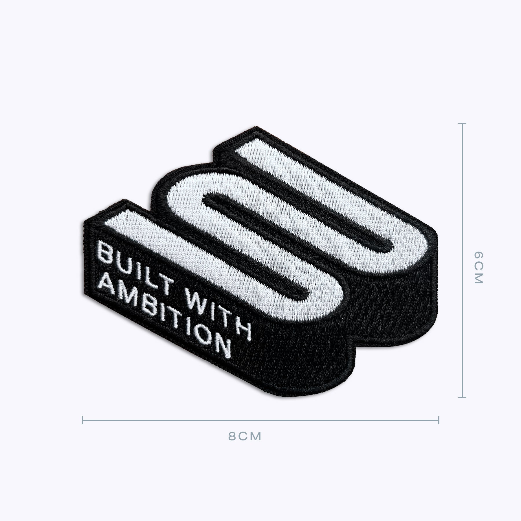 Embroidered patch with bold 3D text and 'Built With Ambition,' size 8x6 cm.