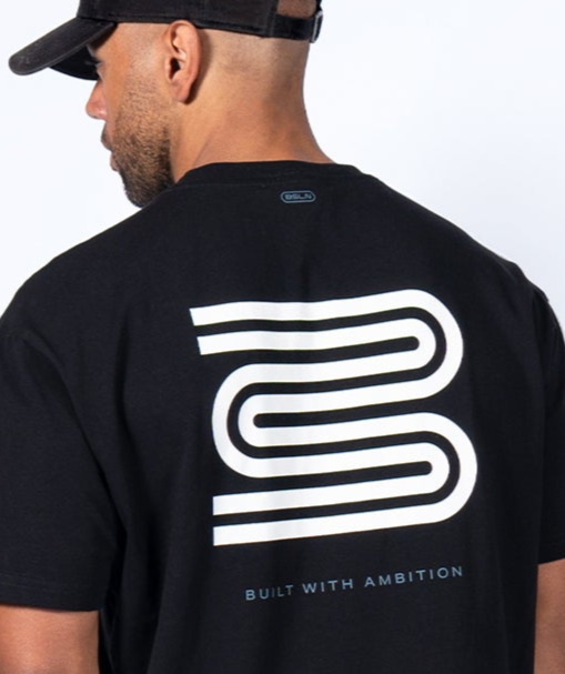 Man wearing a black t-shirt with a white logo and text on the back, on a plain background.