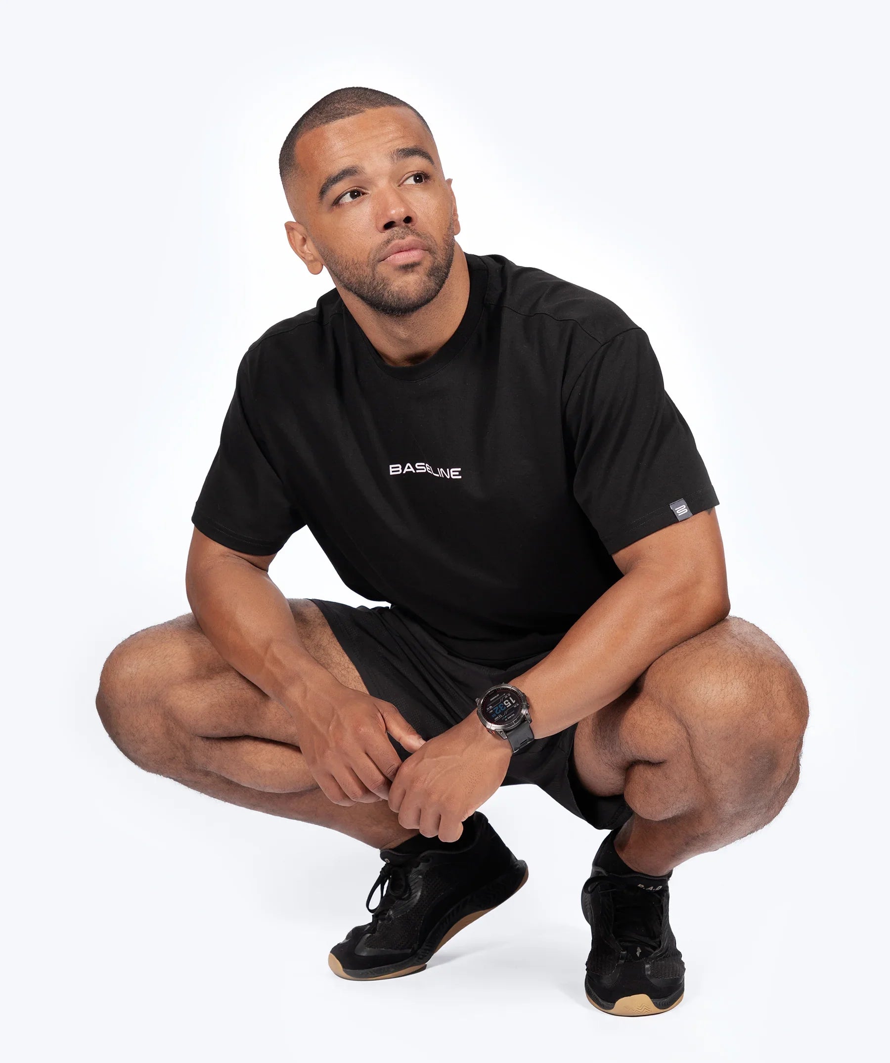 Male athlete wearing a black 'Icon Oversized' t-shirt with a logo on a white background
