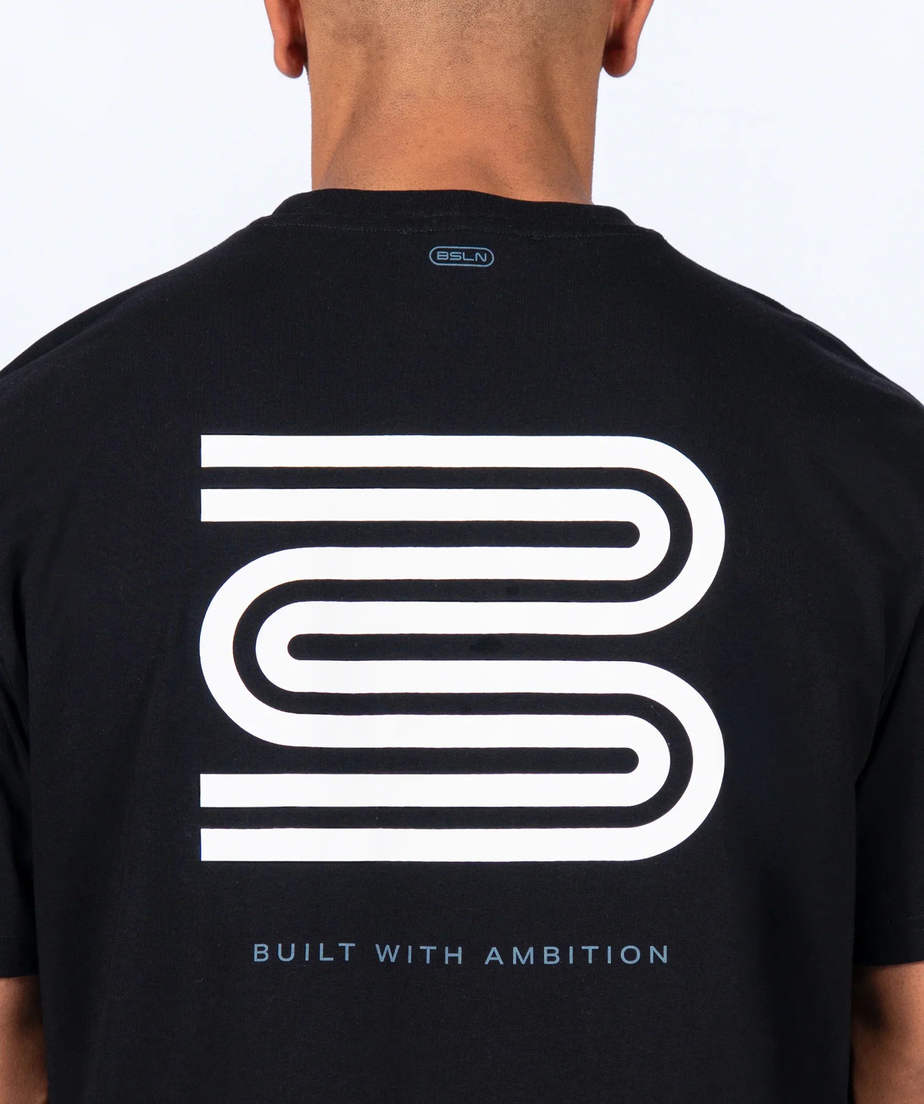 Black 'Icon Oversized' t-shirt with a white logo and text on the back, worn by a person.