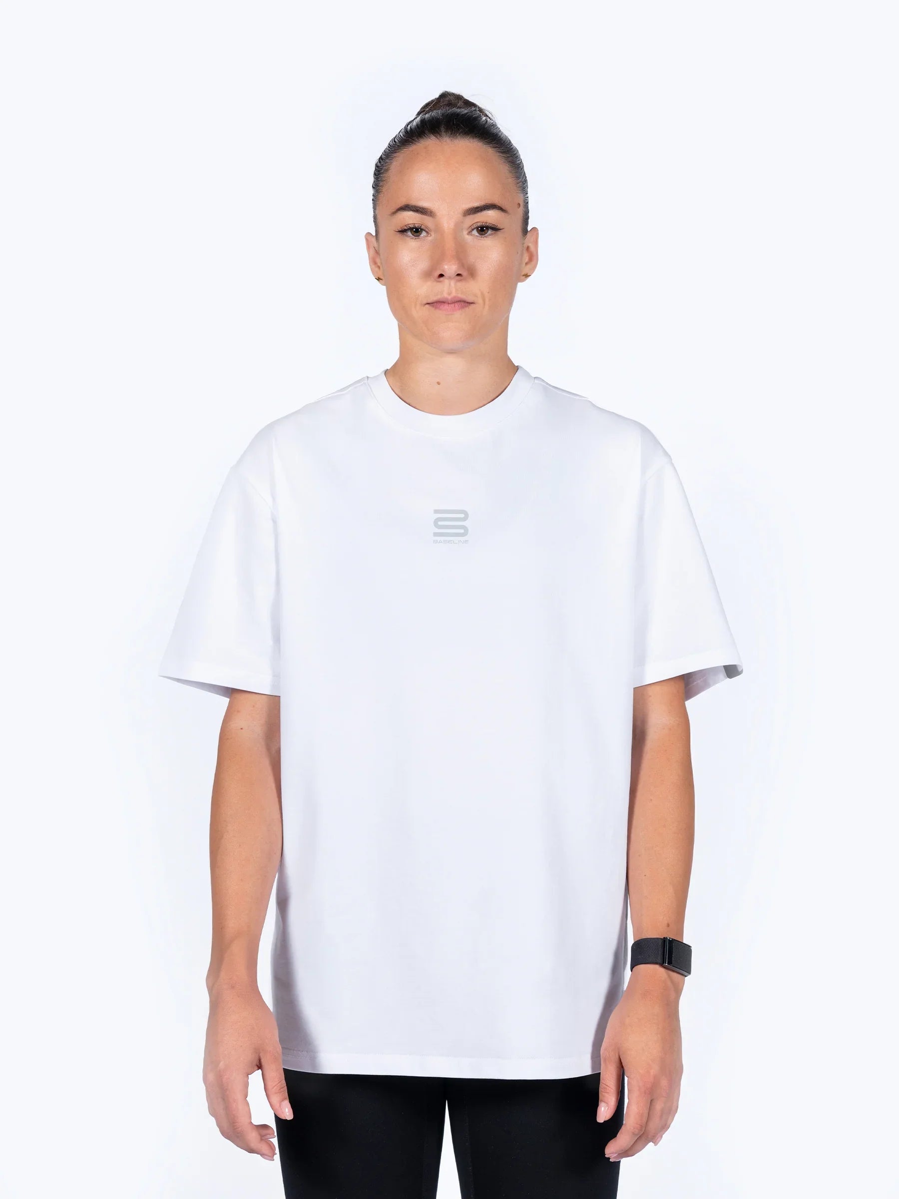 female athlete wearing a white 'Centric Oversized' t-shirt, with a white background