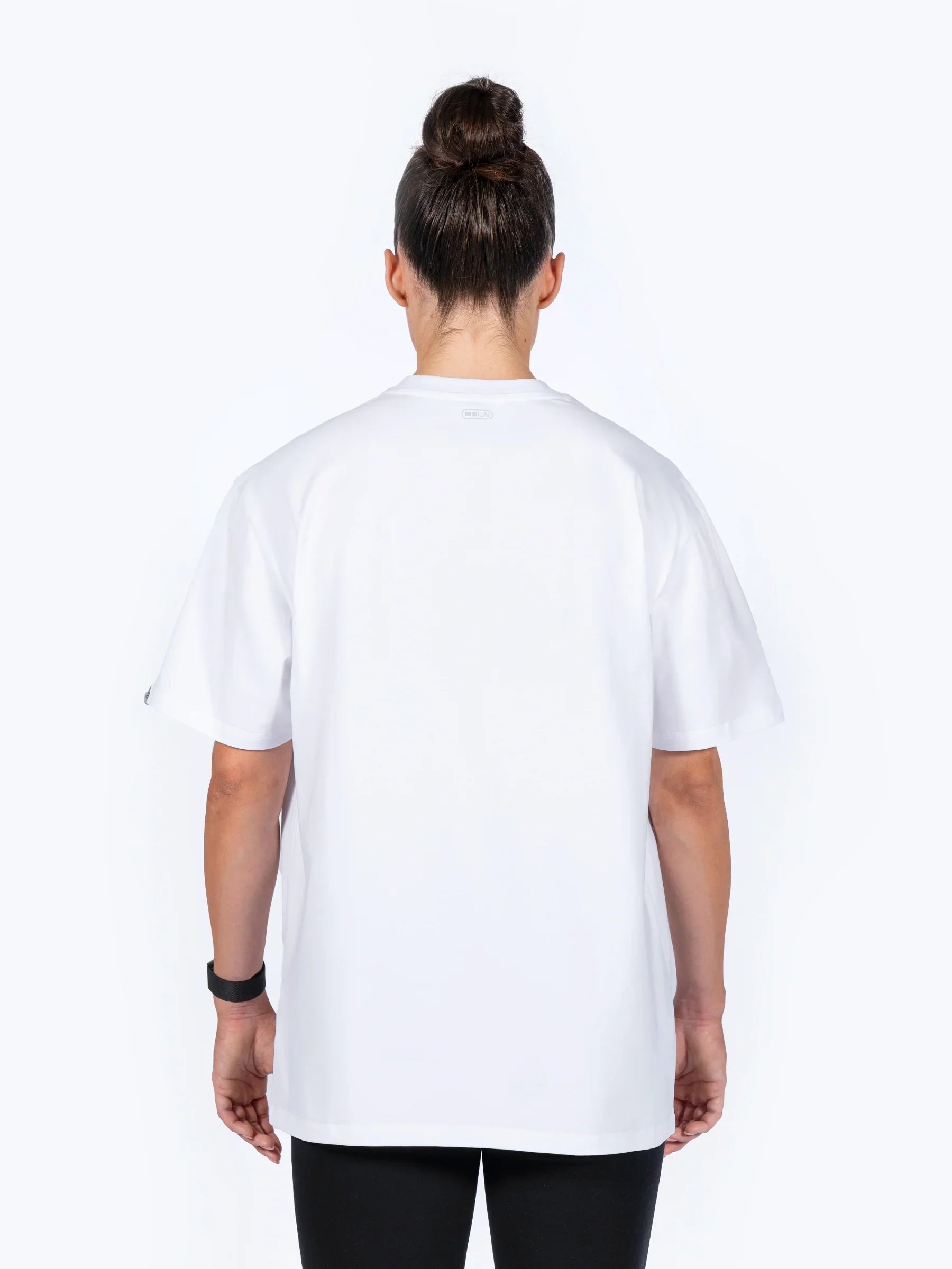 Female athlete wearing white 'Centric Oversized' t-shirt, facing backwards, on a white background
