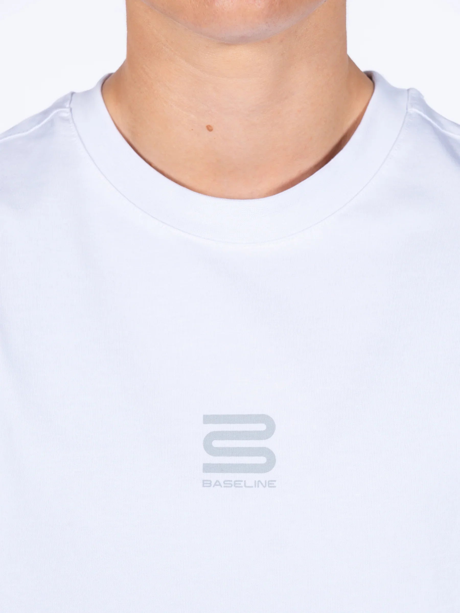 Close-up of a person wearing a white 'Centric Oversized' t-shirt with a Baseline brand logo on a white background
