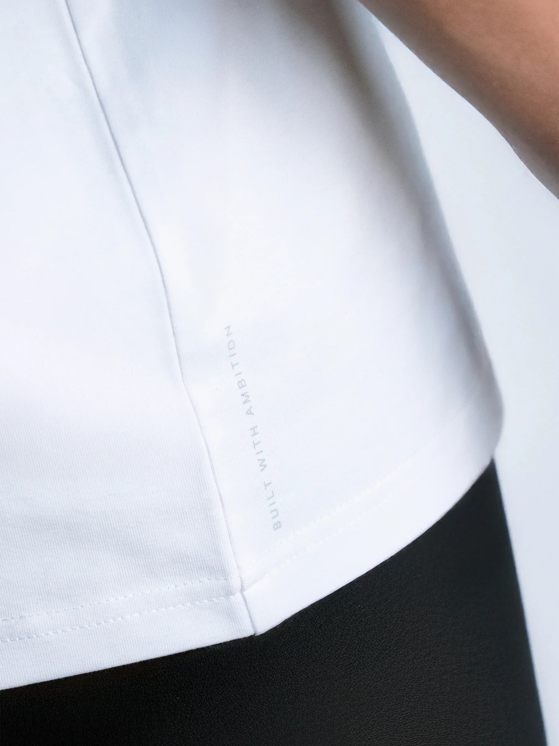 Close-up of a white shirt collar with the 'built with ambition'- phrase and with a blurred background