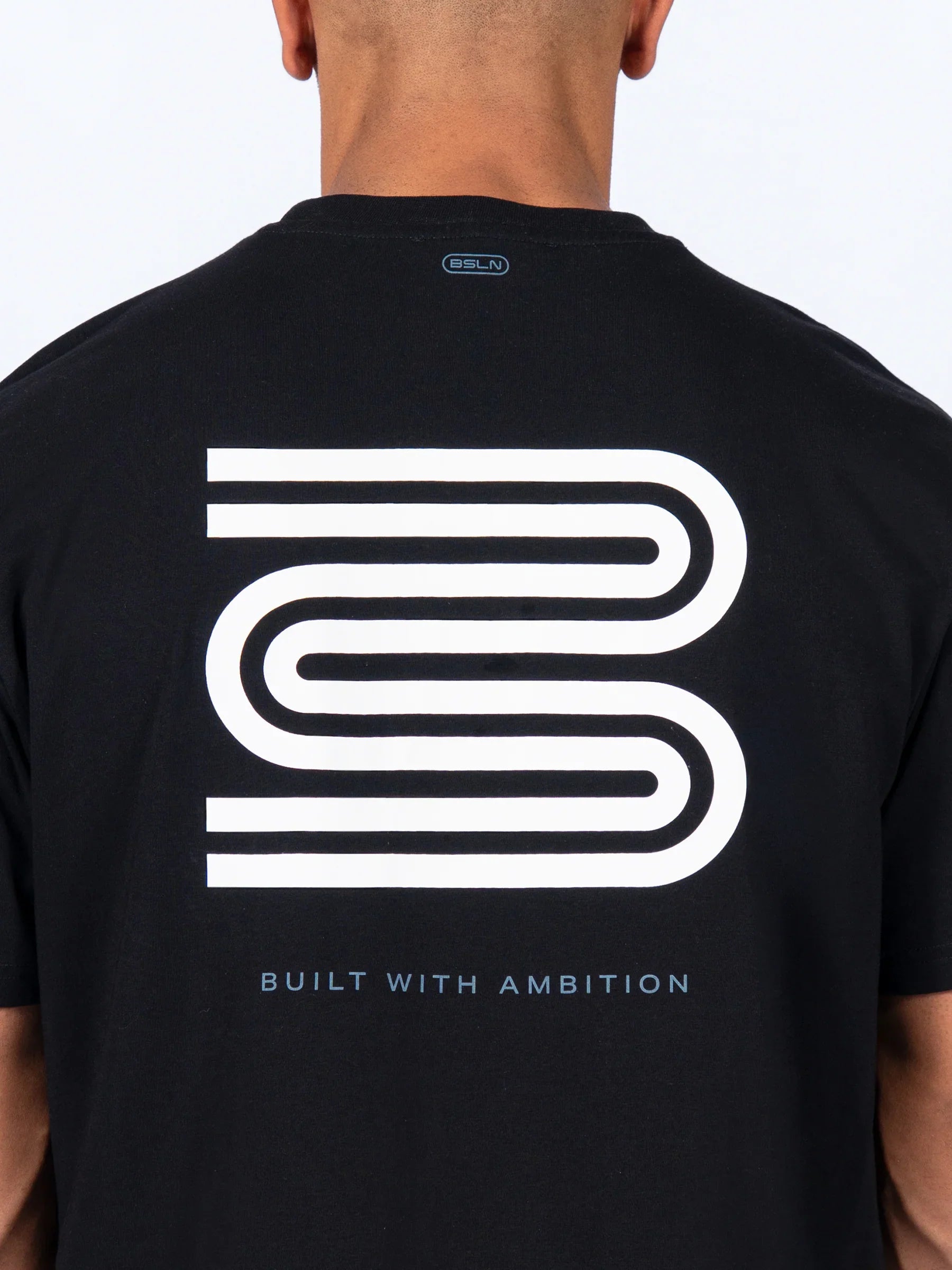 Black 'Icon Oversized' t-shirt with a white 'Baseline' logo and text on the back, worn by a male athlete.